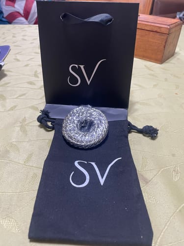Reseñador muestra la Cadena Cuban 10mm enrollada en su bolsa de tela negra, con la bolsa de la tienda detrás.