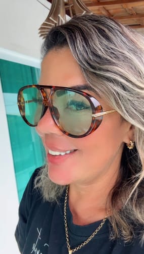 Avaliadora em close-up, usando os Óculos Tropea com sua armação tartaruga e lentes verdes.