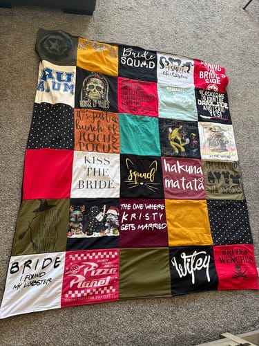 A reviewer's large Project Repat T-Shirt Quilt spread on the floor, showing custom patches with bridal and pop culture themes.