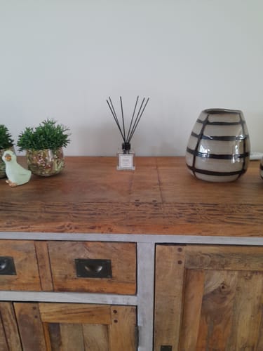 Recensent toont Istanbul Geurstokjes op een houten dressoir met andere woondecoratie.