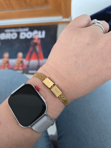 Reviewer wearing the gold mesh Zara Bracelet with two personalized plates on their wrist, next to a smartwatch.