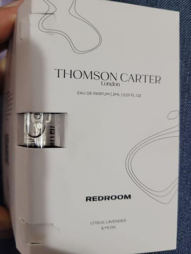Customer holding the white packaging for the Redroom Eau de Parfum 2ml sample, with the vial visible.