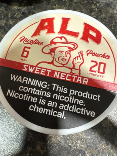 Customer's close-up of the lid on a can of ALP Sweet Nectar Nicotine Pouches, showing the branding and warning label.