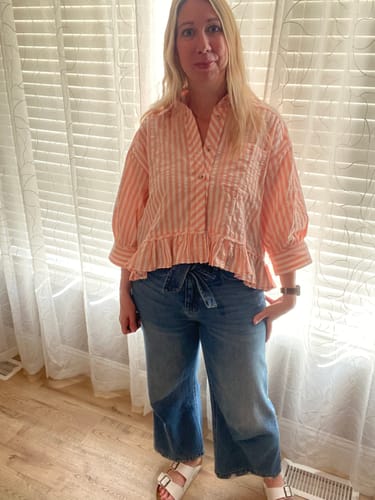 Reviewer wearing the oversized Rainey Button Down Top in peach and white stripes with jeans.