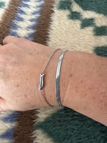 Customer wearing the silver Chelsea Herringbone Bracelet on their wrist, layered with another delicate bracelet.