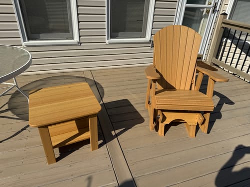 Customer's assembled Adirondack single glider and two-tier end table in a light wood color, placed on an outdoor deck.