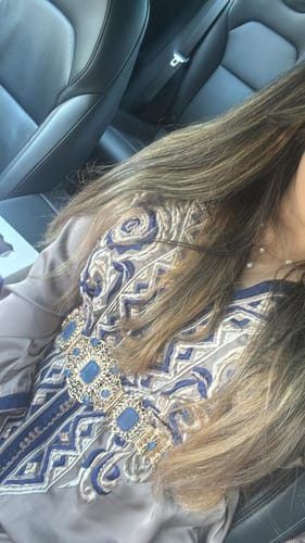 Close-up of a customer wearing the Caftan Sania, showing the intricate blue and gold embroidery and matching belt.