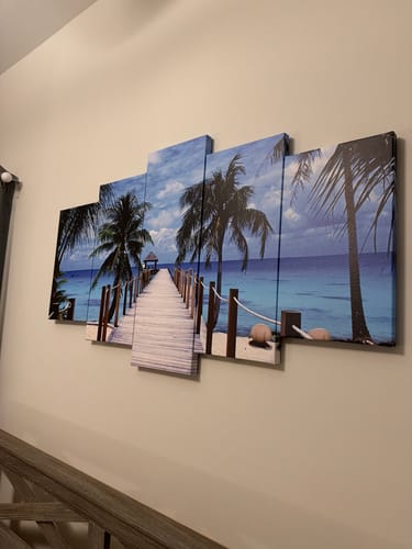 Customer's Pier to Paradise canvas hung at an angle on a light-colored wall in a room.