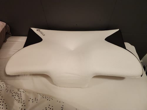 Avis d'un client sur le Coussin d’Alignement Cervical Cellsius blanc et noir, posé à plat sur un lit.