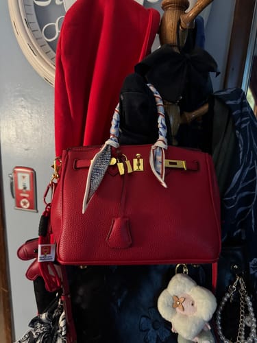 Customer's red pebbled leather Warkin Bag hanging indoors, styled with a decorative scarf on the handle.