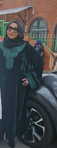 Reviewer standing outdoors wearing the dark green velvet Jumanah, showing the embroidered neckline and its fit.