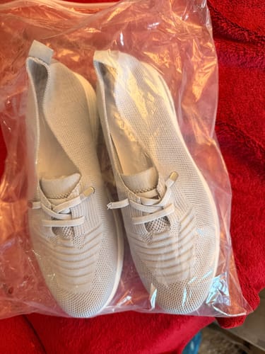 Customer's new light-colored knit slip-on sneakers in their original plastic bag.