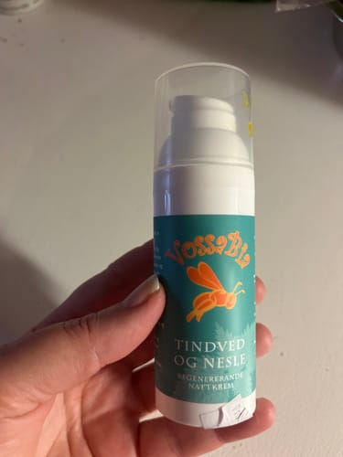 Kunde holder en hvit pumpeflaske med Tindved og nesle-nattkrem i hånden.