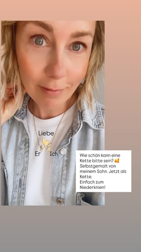 Kundin trägt eine persönliche Halskette mit Kinderzeichnung, die sie zu ihrer Jeansjacke und einem weißen T-Shirt kombiniert.