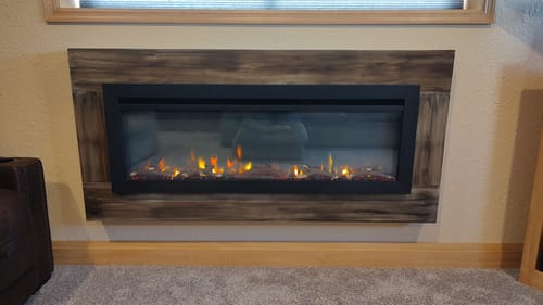 Customer's SimpliFire Allusion fireplace with a custom dark wood-grain surround, showing yellow flames.