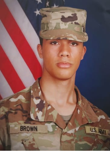 Reviewer's photo of a young soldier in a U.S. Army uniform, in front of an American flag.