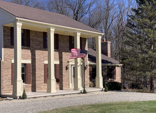 Reviewer's Prestige House Flag Pole kit installed on a pillar of their two-story brick home.