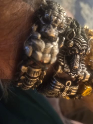 Close-up of a reviewer's wrist wearing two detailed cupronickel bracelets, including the Tiger Paracord Bracelet.
