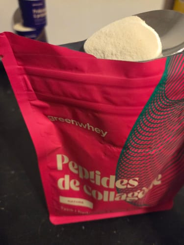 Client montrant le sachet rose de Peptides de Collagène avec une dose de poudre blanche sur le dessus.