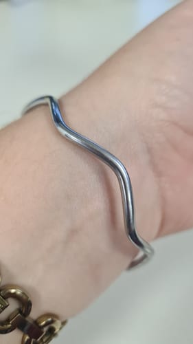 Close-up of a reviewer's wrist wearing the wavy, silver Ripple Bangle.