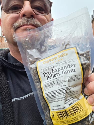 Recensent houdt een zak Captura Baits Pro Expander Pellets 6mm vast.