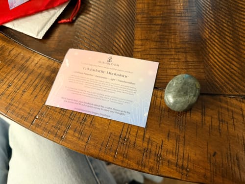 Reviewer's stunning Labradorite Moonstone crystal on a dark wood table next to its information card.