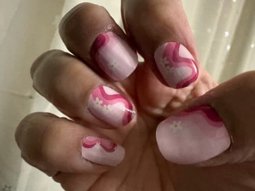 Close-up of a customer's hand showing their nails with the pink, wavy Daisy Paradise nail gels applied.