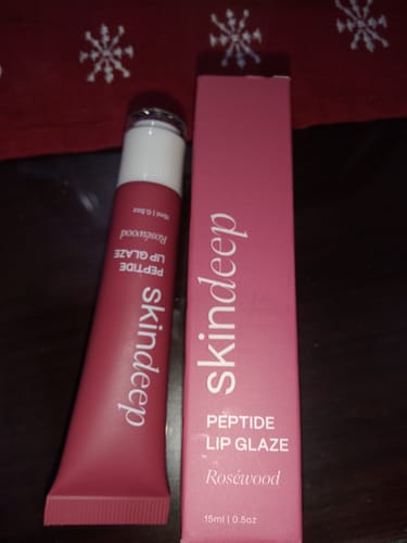 Reviewer's Peptide Lip Glaze in the Rosewood shade. The dusty rose tube stands beside its box.