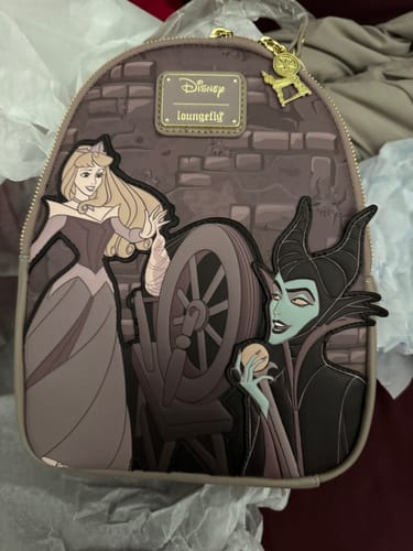 Customer's mauve Loungefly backpack showing the detailed scene of Aurora reaching for the spinning wheel as Maleficent watches.