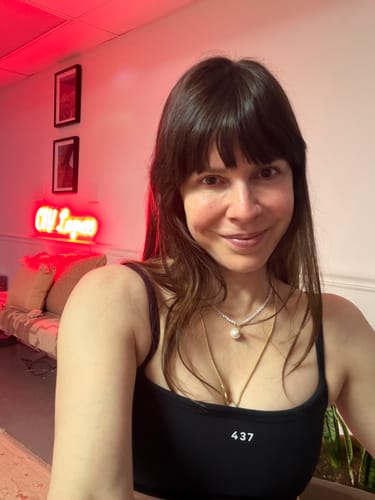 Reviewer taking a selfie in a studio, showing the supportive fit of the black Micro Bra.