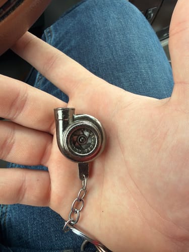 Customer holding the small, metallic Turbo Keychain in the palm of their hand.