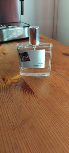 Customer's For Him Pheromone Perfume bottle sitting on a wooden table.