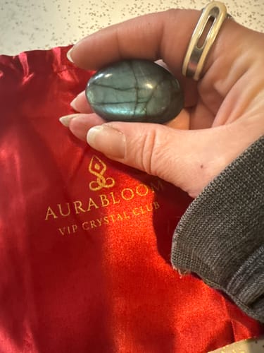 Customer holding a polished labradorite crystal over the red VIP Crystal Club pouch.