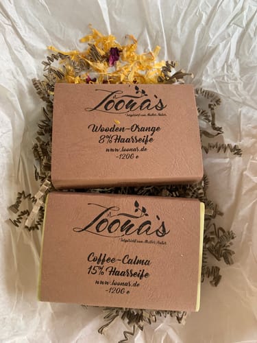 Rezensentenfoto der 8% Wooden-Orange Haarseife, die neben der Coffee-Calma Haarseife auf Füllpapier liegt.