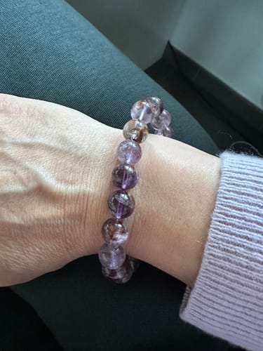 Un client portant le bracelet Auralite 23 à son poignet, montrant ses perles violettes avec des inclusions rouges.