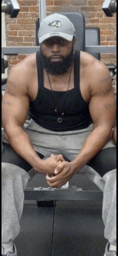 Reviewer resting on a weight bench in a gym. They used Mwendo™ to help recover from an elbow injury.