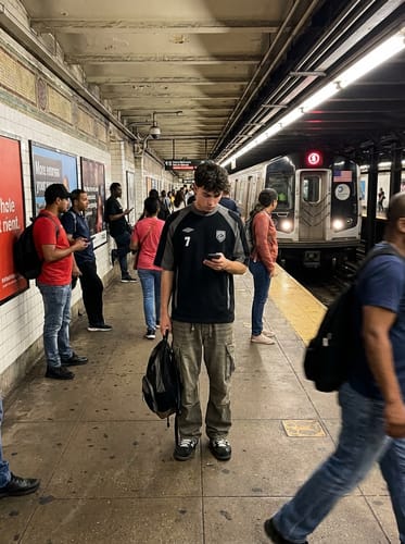 Reviewer on a subway platform wearing the sporty color-block t-shirt in black and grey with an embroidered number 7.