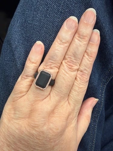 A customer's hand wearing the Emerald Silicone Ring, showing its black band and stylish metal frame with CZ stones.