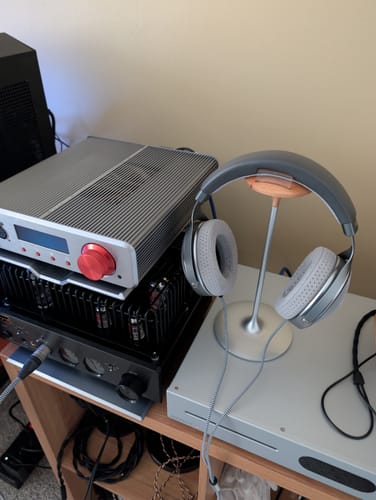 Reviewer's Focal Clear Headphones on a silver stand next to a stack of audio amplifier equipment.