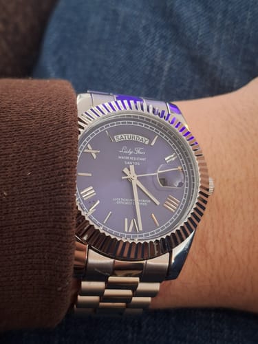 A close-up of a customer wearing the Lucky Fours® Santos watch, showing the blue dial and silver band.