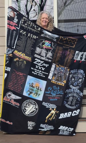 Customer proudly displaying their large, black T-Shirt Quilt made from various rock band concert t-shirts.