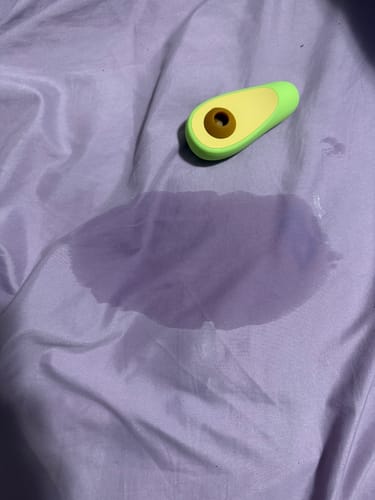 Customer's Avo Clitoral Massager on a purple sheet next to a large wet spot, implying the result mentioned in the review.