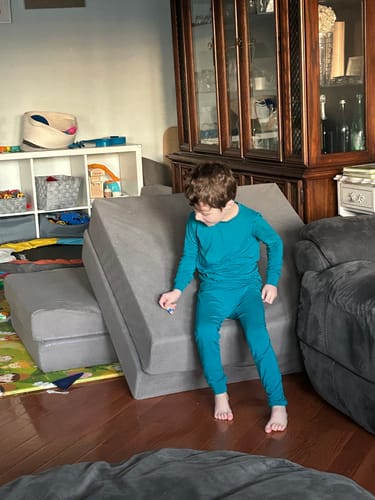 Customer's child wearing the teal, snug Nautical Kids Bamboo PJs while playing in a living room.
