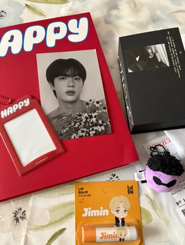 Customer shows items from their K-POP RANDOM BOX, including a Jin photocard, Jimin lip balm, and a keychain.