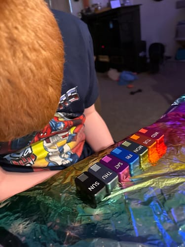 A customer's son looks at the colorful MagNano Case, with the metal pill containers lined up for each day of the week.