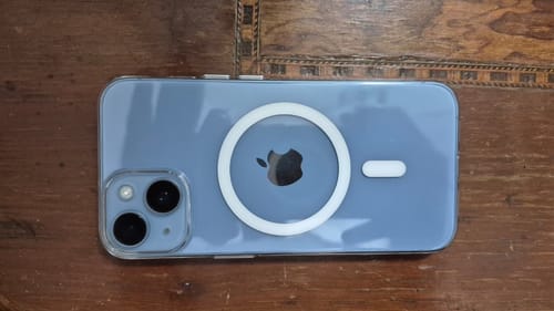 Reviewer's Anti Yellow Magsafe case on a blue iPhone 14, showing its clear finish and white MagSafe ring.