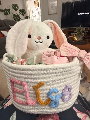 Customer's fluffy white animal plushie toy, a bunny, sitting in a personalized basket with other gifts.