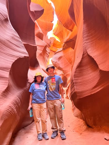 Reviewer and their son wearing their matching blue Blessed Are The Curious Tees inside a narrow slot canyon.