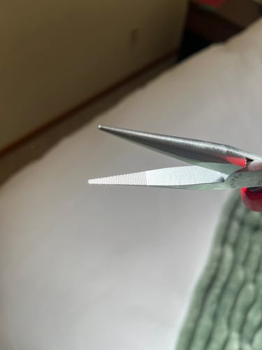 Close-up of a reviewer's Knipex pliers, showing the cross-hatched gripping surface on the slim jaws.