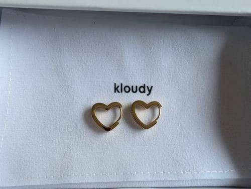Customer's gold Dainty Heart Hoop Earrings displayed on a white pouch inside the box.